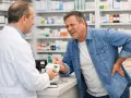 Farmacista consegna farmaco a uomo con mal di schiena, preoccupato per la terapia del dolore schiena effetti collaterali.