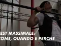 Uomo con giubbotto zavorrato esegue trazioni alla sbarra. Il testo "TEST MASSIMALE: COME, QUANDO E PERCHÈ" suggerisce una guida per la tabella massimali palestra.