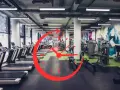 Una palestra moderna con tapis roulant e macchine per il fitness. Un grande orologio rosso sovrapposto suggerisce gli orari migliori per andare in palestra.