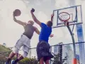 Due giocatori di basket in aria, uno schiaccia la palla, l'altro tenta di bloccarlo. Un perfetto equilibrio energetico in campo.