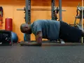 Uomo in posizione di plank, allenamento per i muscoli del core in palestra.