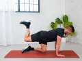 Uomo in posizione a quattro zampe su un tappetino rosso, esegue un esercizio di ginnastica per anca sollevando una gamba piegata.