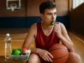 Giovane giocatore di basket mangia verdure, pensando a quali carboidrati sono essenziali per la sua energia.