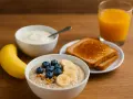 Colazione nutriente per ultra trail: porridge con frutta, yogurt, toast e succo d'arancia.