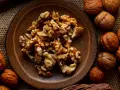 Noci sgusciate in un piatto marrone e noci intere sparse. Quante noci al giorno fanno bene alla salute?