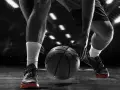 Giocatore di basket in azione, concentrato sul palleggio. Allenarsi per migliorare il fiato è fondamentale per vincere.