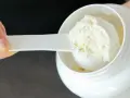Mano che preleva proteine in polvere da un barattolo bianco con un misurino. Ideale per il recupero post-allenamento.
