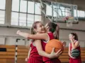Due giocatrici di basket si abbracciano, una tiene un pallone. Forse si allenano con esercizi mobilità anche e bacino.