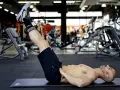 Uomo muscoloso esegue reverse crunch su panca in palestra, concentrato sull'allenamento addominale.