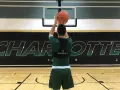 Basketball player in green uniform shooting a basketball in a gym with "CHARLOTTE" logo on the wall.