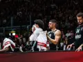 Giocatori di basket in panchina, asciugandosi il sudore con asciugamani. Un promemoria che anche gli atleti hanno bisogno di recupero e proteine in un giorno intenso.