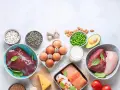 Varietà di alimenti ricchi di zinco: fegato, carne rossa, pollo, salmone, gamberi, uova, fagioli, semi di zucca, piselli, mandorle, avocado, formaggio, latte, aglio e grano saraceno.
