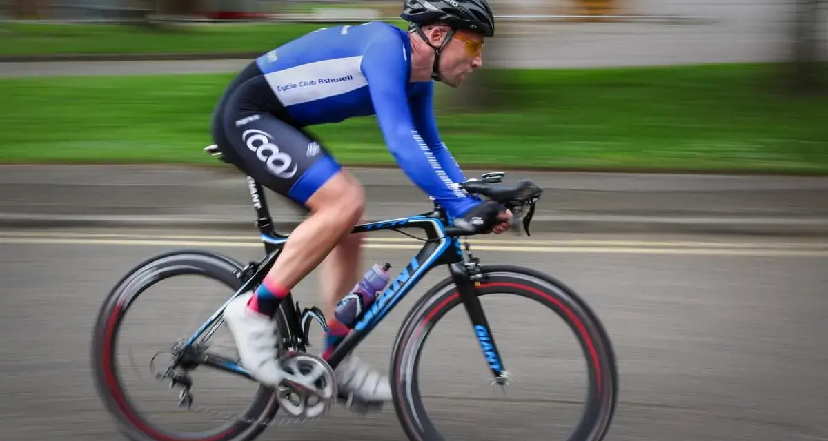 Ciclista in gara, i suoi muscoli delle gambe lavorano intensamente per spingere i pedali.