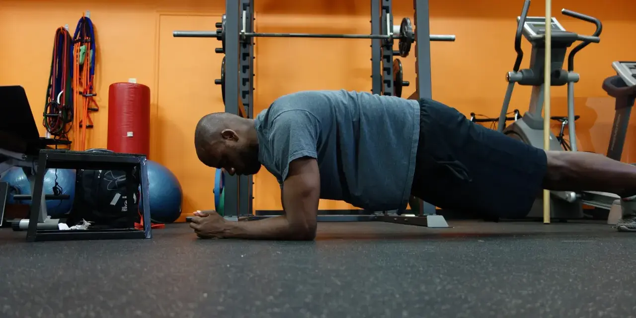 Uomo in posizione di plank, allenamento per i muscoli del core in palestra.