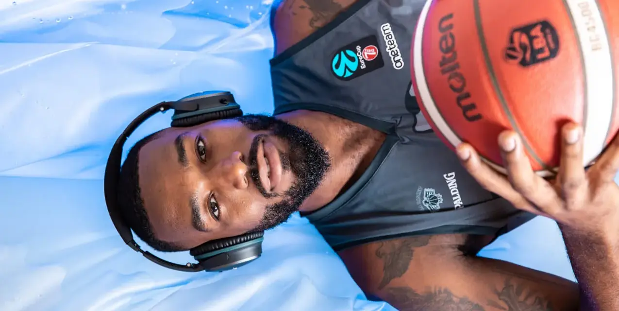 Giocatore di basket con cuffie e pallone, pronto per la preparazione fisica.