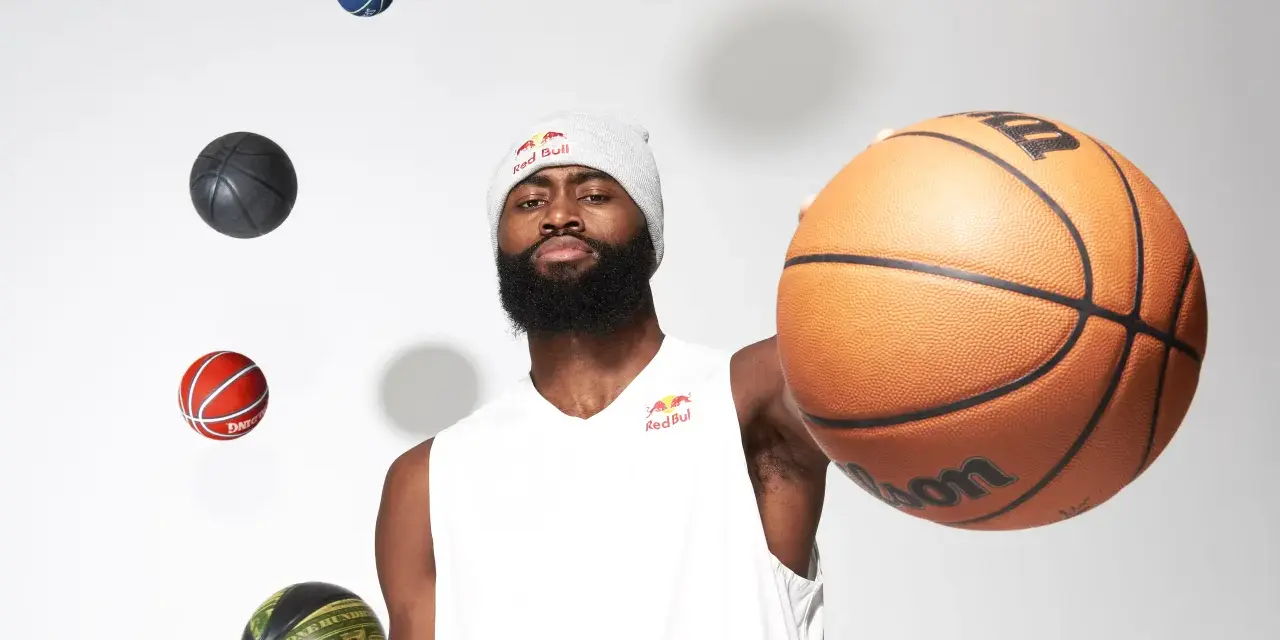 Un giocatore di basket con un berretto Red Bull, circondato da palloni che sembrano fluttuare. Prendi un respiro profondo, inspira ed espira, pronto per il gioco.