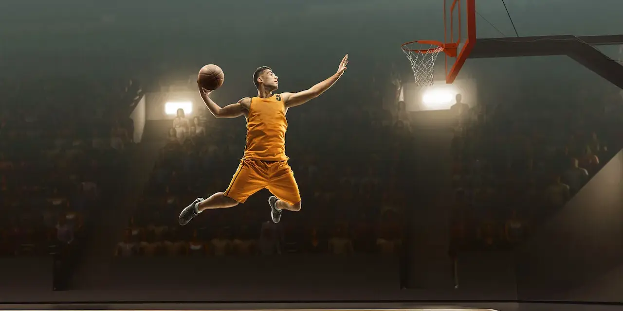 Un giocatore di basket in aria, pronto a schiacciare, sembra quasi fermo nel tempo per riprendere fiato prima del grande momento.