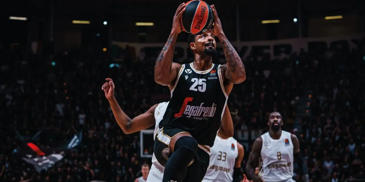 Giocatore di basket con palla in alto, pronto al tiro. Per mantenere la forma fisica, è importante sapere come calcolare le proteine da assumere.