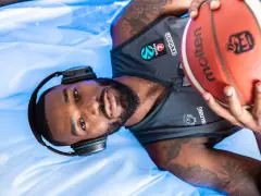 Giocatore di basket con cuffie e pallone, pronto per la preparazione fisica.