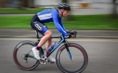 Ciclista in gara, i suoi muscoli delle gambe lavorano intensamente per spingere i pedali.