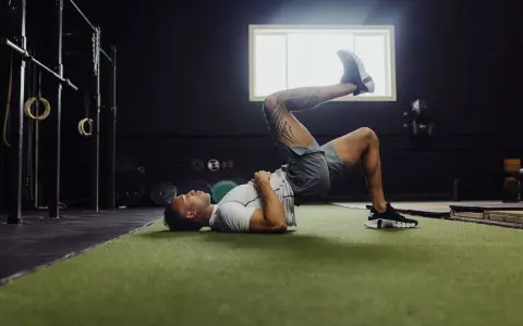 Uomo esegue ponte per gamba singola, un esercizio utile per la fisioterapia per ernia del disco, in palestra.
