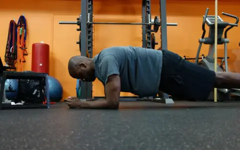 Uomo in posizione di plank, allenamento per i muscoli del core in palestra.