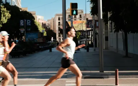 Corridori in città, un uomo corre con un semaforo pedonale verde. Il **talk test** è superato, respira bene.