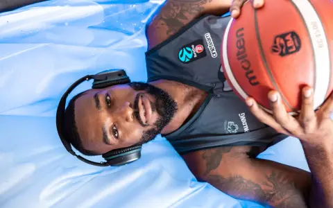 Giocatore di basket con cuffie e pallone, pronto per la preparazione fisica.