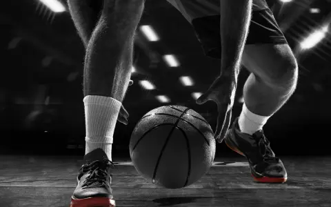 Giocatore di basket in azione, concentrato sul palleggio. Allenarsi per migliorare il fiato è fondamentale per vincere.