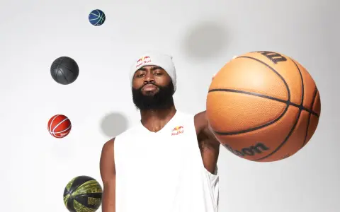 Un giocatore di basket con un berretto Red Bull, circondato da palloni che sembrano fluttuare. Prendi un respiro profondo, inspira ed espira, pronto per il gioco.