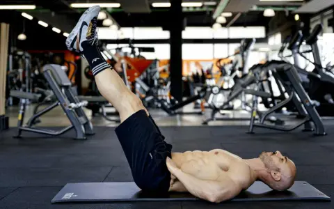Uomo muscoloso esegue reverse crunch su panca in palestra, concentrato sull'allenamento addominale.