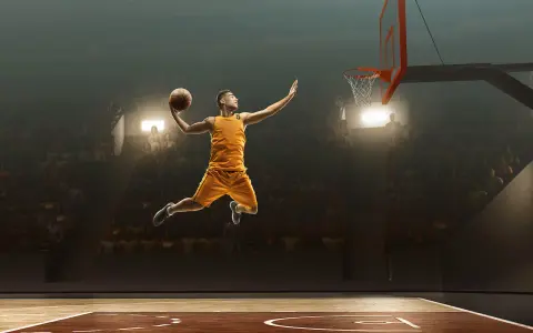 Un giocatore di basket in aria, pronto a schiacciare, sembra quasi fermo nel tempo per riprendere fiato prima del grande momento.