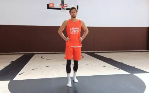 Giovane giocatore di basket in tenuta arancione, pronto per esercizi per i piedi sul campo.