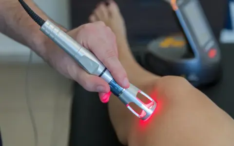 Trattamento con laser su ginocchio. La laserterapia è sicura, ma alcuni effetti collaterali lievi sono possibili.