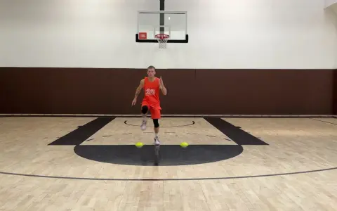 Giovane atleta in divisa arancione esegue uno degli **10 esercizi di riscaldamento** su un campo da basket, con coni gialli a terra.