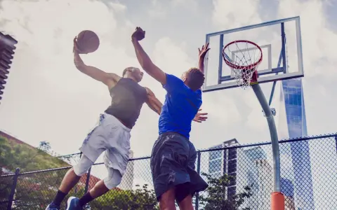 Due giocatori di basket saltano per un canestro. L'energia che li spinge, come i carboidrati complessi quali sono, è visibile in ogni movimento.