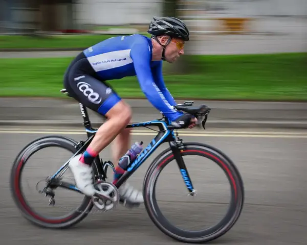 Ciclista in gara, i suoi muscoli delle gambe lavorano intensamente per spingere i pedali.