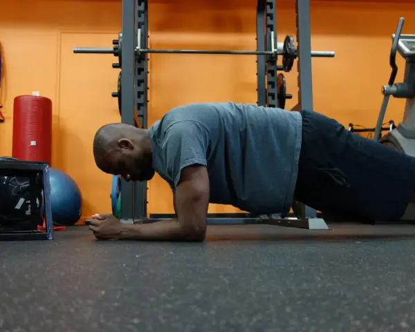 Uomo in posizione di plank, allenamento per i muscoli del core in palestra.