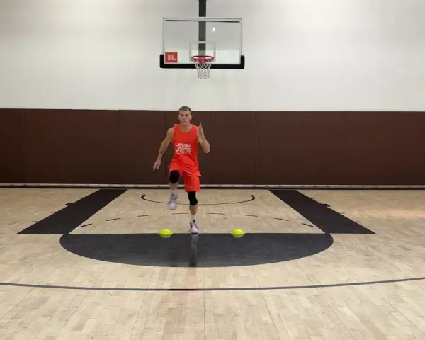 Giovane atleta in allenamento su un campo da basket, dimostra la sua **forza resistente** con un esercizio di corsa sul posto.