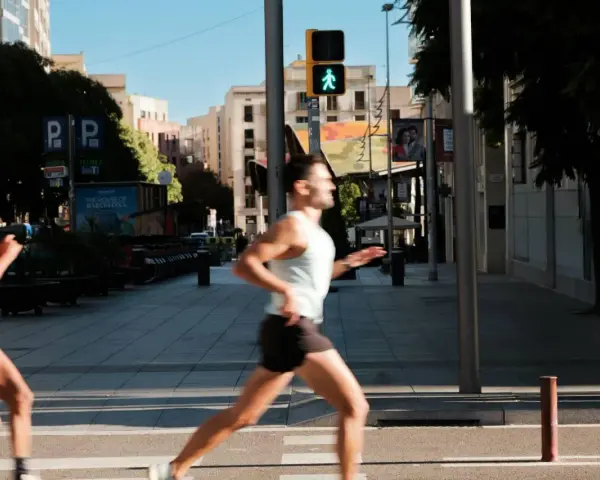 Corridori in città, un uomo corre con un semaforo pedonale verde. Il **talk test** è superato, respira bene.