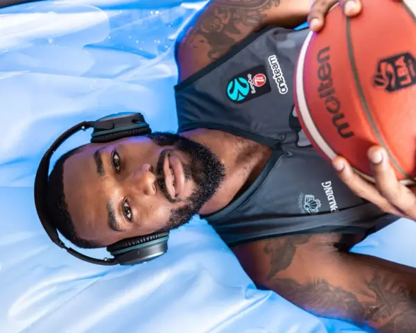 Giocatore di basket con cuffie e pallone, pronto per la preparazione fisica.