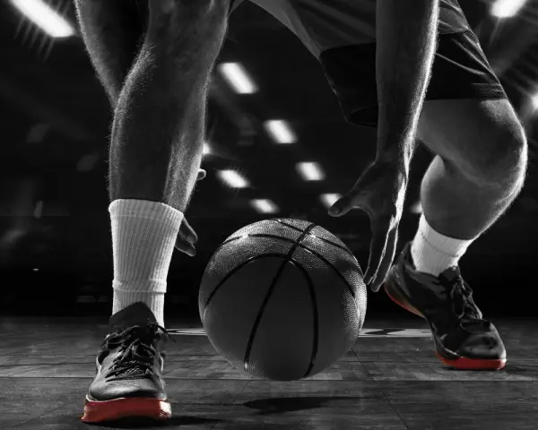 Giocatore di basket in azione, concentrato sul palleggio. Allenarsi per migliorare il fiato è fondamentale per vincere.