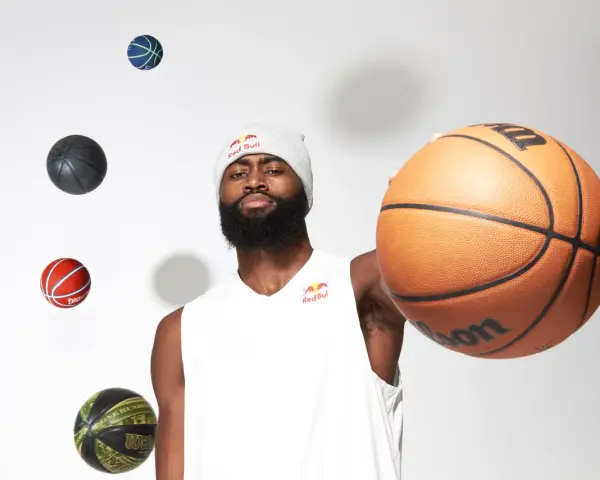 Un giocatore di basket con un berretto Red Bull, circondato da palloni che sembrano fluttuare. Prendi un respiro profondo, inspira ed espira, pronto per il gioco.
