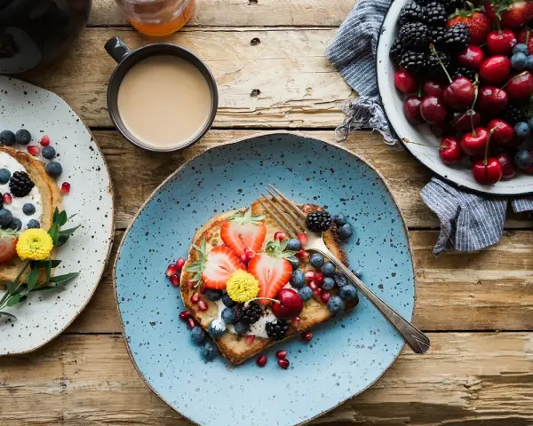 Toast con frutta fresca e yogurt, una colazione energetica per sportivi. Frutti di bosco, fragole e ciliegie per iniziare la giornata con vitalità.