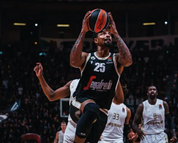 Giocatore di basket con palla in alto, pronto al tiro. Per mantenere la forma fisica, è importante sapere come calcolare le proteine da assumere.