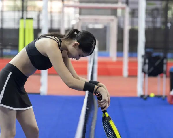 Giocatrice di padel esausta, forse cerca rimedi naturali per il dolore all'anca dopo l'allenamento.