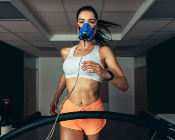 Donna corre su tapis roulant con maschera per misurare il VO2 max.