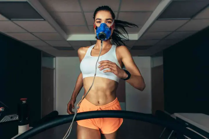 Donna corre su tapis roulant con maschera per misurare il VO2 max.