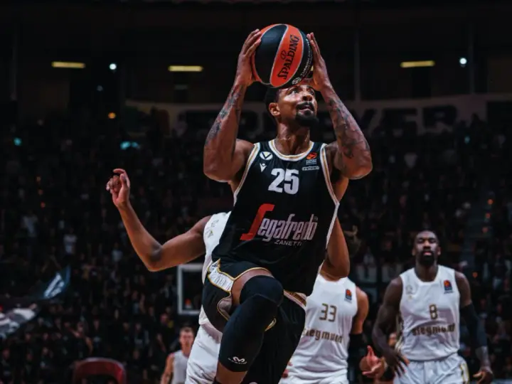 Giocatore di basket con palla in alto, pronto al tiro. Per mantenere la forma fisica, è importante sapere come calcolare le proteine da assumere.