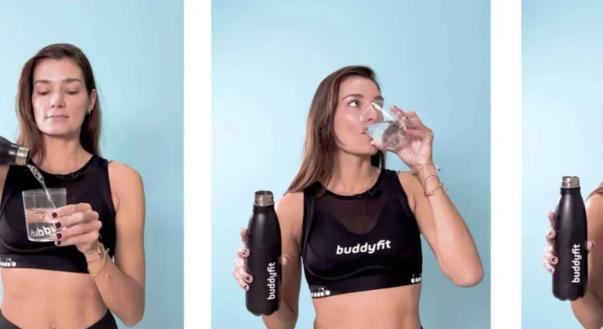 Donna si idrata con acqua, essenziale per chi assume creatina in estate. Mantiene la sua forma fisica con stile.